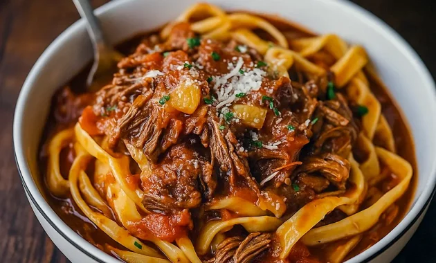 A bowl of pasta topped with rich Beef Ragu Recipe from a slow cooker, garnished with Parmesan and parsley, showcasing a comforting Slow Cooker Dinner perfect for hearty meals.