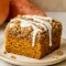 Overhead slice of pumpkin coffee cake with thick streusel topping and drizzle of glaze on a white plate.