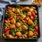Sheet pan of bite-sized glazed chicken, roasted bell peppers, red onion and toasted cashews, served with a side of steamed rice.