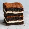 Close-up of a fudgy, dark brownie square made with Greek yogurt, showing a moist crumb and glossy top on a white plate.