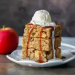 A stack of gooey Cinnamon Apple Blondies with visible apple chunks and cinnamon swirls, resembling Apple Blondie Brownies — a cozy Desserts For Winter treat that’s rich, chewy, and full of Apple Spice flavor.