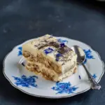 Close-up of layered mascarpone and tea-soaked ladyfingers topped with powdered tea and cornflower petals — a floral Tea Tiramisu, showcasing the elegant Earl Grey Tiramisu ideal for a refined Tea Dessert.