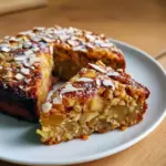 Slice of oatmeal apple cake on a plate, topped with a drizzle of honey and a sprinkle of oats, showing tender crumbs and apple pieces.