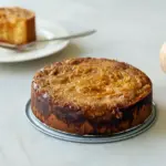 Slice of pumpkin gooey butter cake with a golden crust and creamy, custard-like pumpkin center dusted with powdered sugar on a white plate.