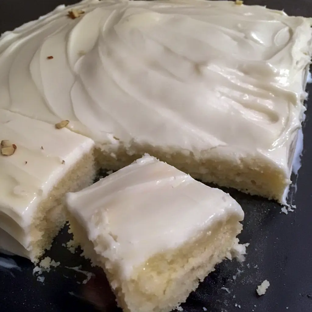 Almond Sheet Cake Recipe: Golden almond sheet cake in a greased Sheet Cake Pan, sliced like a Dessert Bar, topped with glaze, chopped nuts and mini Marshmallows, a tempting photo for fans of Sheet Cake Recipes, Almond Cakes, Food Cakes, Yummy Sweets and other Decadent Cakes.