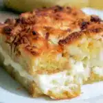 Warm slice of coconut cheesecake bread pudding topped with toasted coconut.