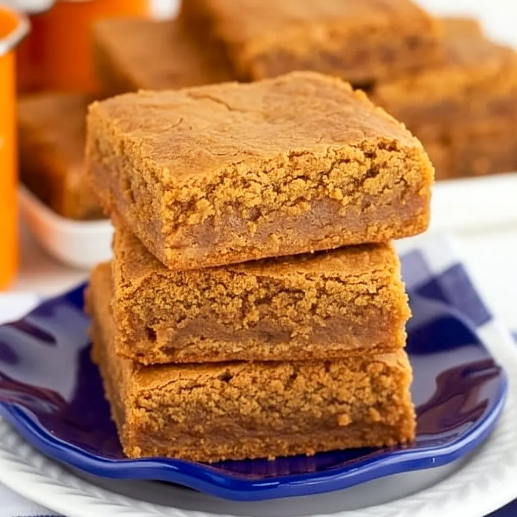 Stack of chewy pumpkin blondies with visible cinnamon chips, drizzled caramel, and a sprinkle of flaky sea salt on a rustic wooden board, Pumpkin Spice Blondies.