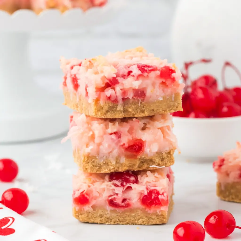 Close-up of glossy Cherry Coconut Bars on a wooden board, showing toasted coconut and sticky cherry filling — ideal as a Cherry Chews Recipe or nostalgic Cherry Nut Bars treat. These bite-sized Cherry Dream Bars (perfect as a Cherry Dream Squares Recipe) look like candy-level Cherry Chews and echo a classic Coconut Chewies Recipe. Gooey Cherry Magic Bars and the simple Cherry Coconut Squares Recipe make beautiful Christmas Coconut Bars for cookie exchanges; imagine Cherry Blossom Bars, a cozy Cherry Coconut Dessert, stacked Cherry Dream Squares, or retro Maraschino Cherry Bars on the same platter.