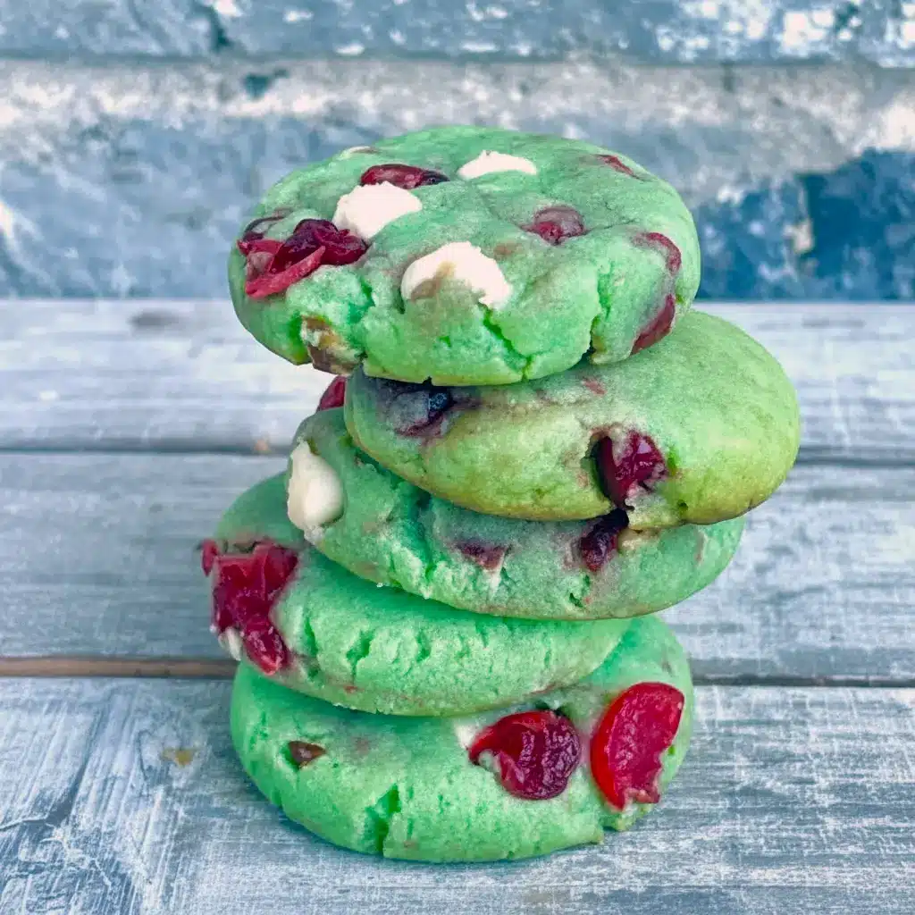 Close-up shot of green crinkle cookies filled with cherries and white chocolate chips, showcasing festive Pistachio And Cherry flavor with the cozy texture of Pistachio Cherry Meltaways, Pistachio Cherry Meltaway Cookies, and Pistachio Pudding Cherry Cookies, styled with the fruity look of Dried Cherry Pistachio Cookies, perfect for fans of Cherry Cookies Recipes, Pistachio Recipes, Cherry Cookies, and soft Pistachio Cookies.