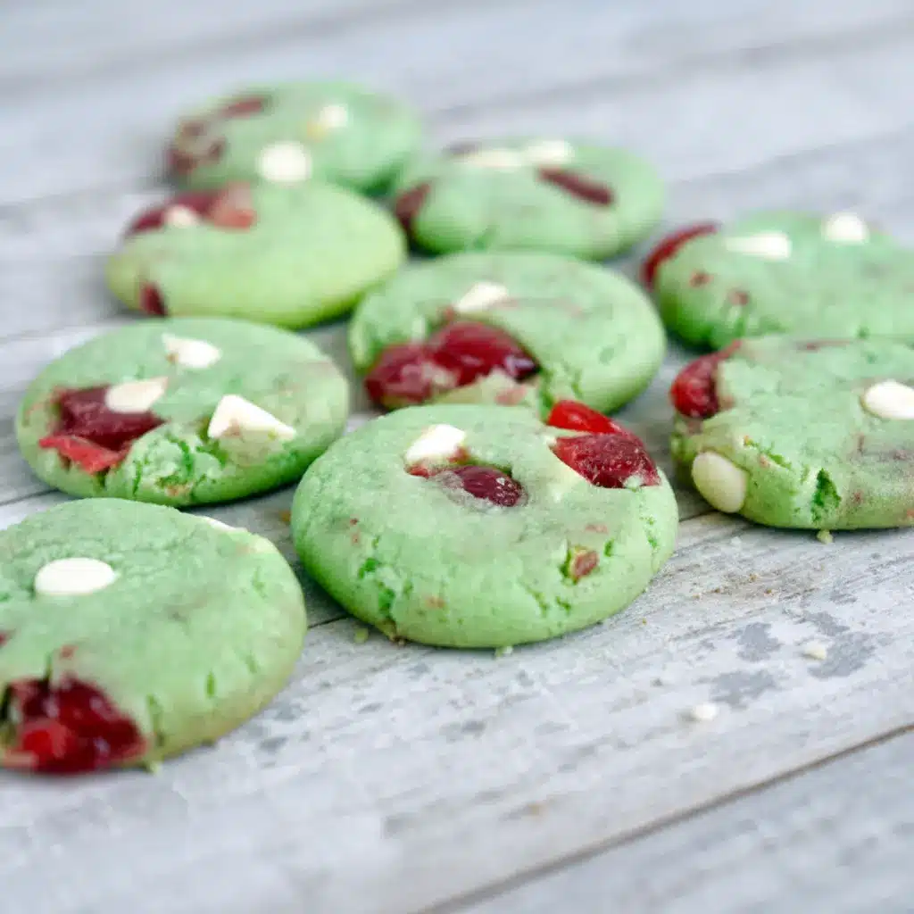 Close-up shot of green crinkle cookies filled with cherries and white chocolate chips, showcasing festive Pistachio And Cherry flavor with the cozy texture of Pistachio Cherry Meltaways, Pistachio Cherry Meltaway Cookies, and Pistachio Pudding Cherry Cookies, styled with the fruity look of Dried Cherry Pistachio Cookies, perfect for fans of Cherry Cookies Recipes, Pistachio Recipes, Cherry Cookies, and soft Pistachio Cookies.
