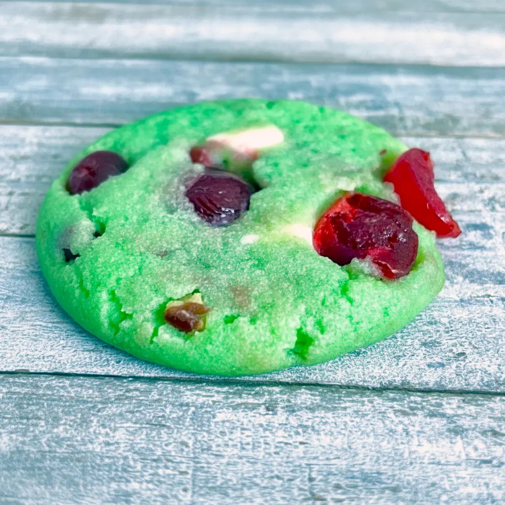 Close-up shot of green crinkle cookies filled with cherries and white chocolate chips, showcasing festive Pistachio And Cherry flavor with the cozy texture of Pistachio Cherry Meltaways, Pistachio Cherry Meltaway Cookies, and Pistachio Pudding Cherry Cookies, styled with the fruity look of Dried Cherry Pistachio Cookies, perfect for fans of Cherry Cookies Recipes, Pistachio Recipes, Cherry Cookies, and soft Pistachio Cookies.