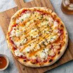 Specialty Pizza Recipes — hot honey-drizzled pizza with ricotta dollops, melted cheese, basil, and a golden, blistered crust.