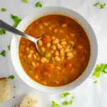 A bowl of Fasolatha, a traditional Greek Vegan Soup made with White Beans, tomatoes, and olive oil, served with rustic bread — a hearty comfort dish from Greek Recipes perfect for Soup And Salad lovers and fans of Здоровое Питание.