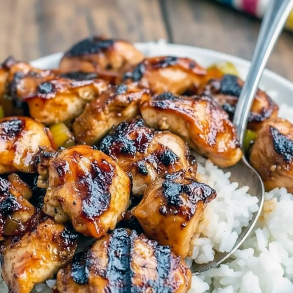 Hawaiian Dishes — grilled Huli Huli chicken thigh glazed with shiny pineapple-soy sauce, sliced and served over white rice with a sprinkle of green onion.