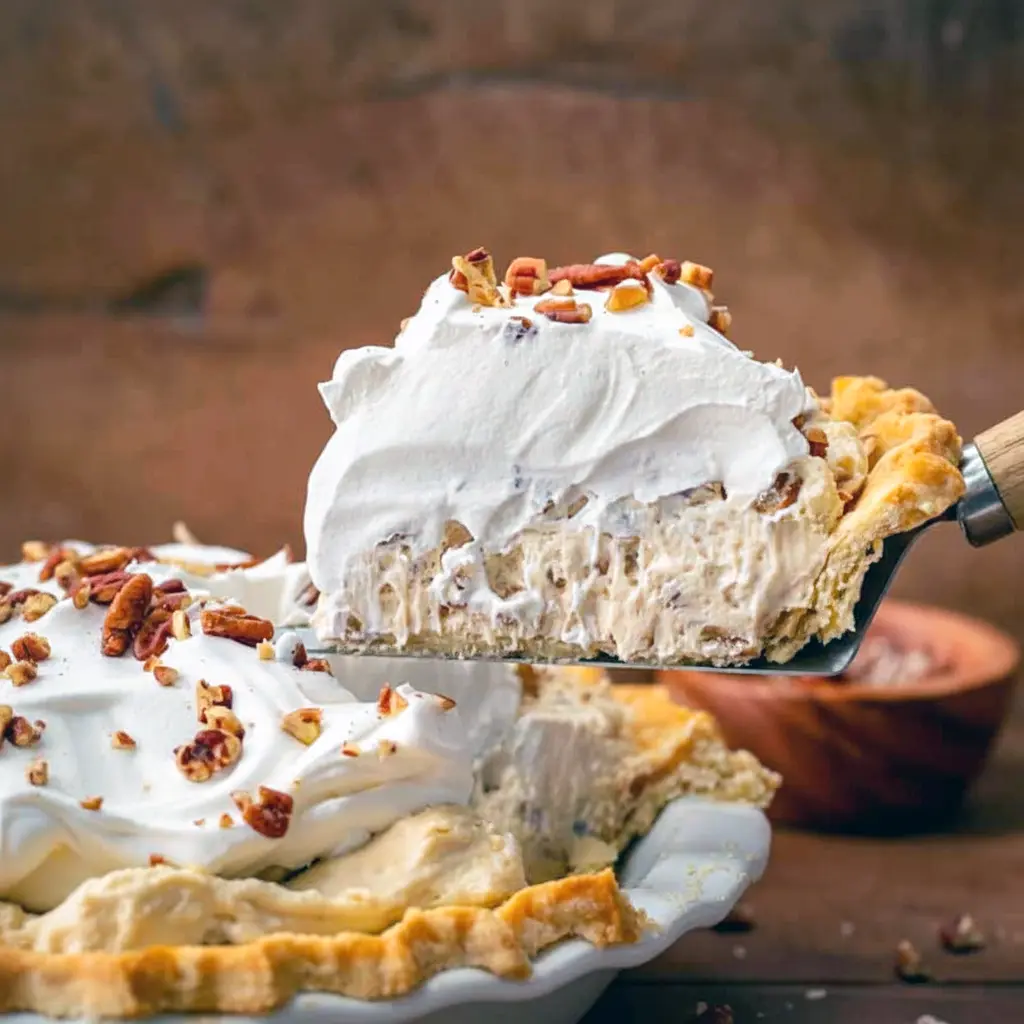 Close-up of a slice topped with whipped cream and toasted pecans: Creamy Pecan Pie Recipe on a flaky crust, shot from the side to show layers — the ultimate Pecan Cream Pie Recipe for festive gatherings.