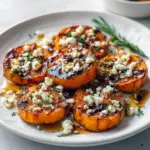 Thanksgiving Ideas Food Side Dishes — close-up of golden roasted sweet potato rounds topped with crumbled feta, a honey drizzle, and chopped parsley on a rustic platter.