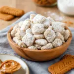 Close-up of Biscoff puppy chow: Chex cereal clusters coated in chocolate-cookie butter and powdered sugar, piled in a rustic bowl, Puppy Chow Different Flavors.