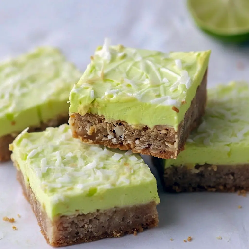 Squares of lime-frosted coconut bars with shredded coconut and a white chocolate drizzle on a festive serving board, Starbucks Bars.