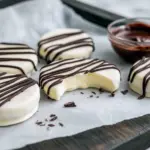 Close-up of round peppermint creams with glossy dark chocolate zig-zags on top, arranged on a festive plate with a light dusting of powdered sugar, Homemade Peppermint Treats.