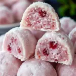 Close-up of powdered-sugar coated cherry cookies on a festive plate, with chopped pecans and red holiday sprinkles, Cherry Snowball Cookies Recipe.