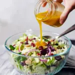 Close-up of shredded cabbage slaw with dried cranberries and toasted almonds, drizzled in vinaigrette — great for Aderezos Para Ensaladas, shown as a simple Slaw Recipes idea and a bright option among Thanksgiving Dishes and Thanksgiving Sides, Fall Coleslaw With Apples.