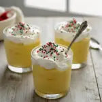 Close-up of a creamy dessert in a glass, crowned with whipped cream and a dusting of nutmeg — festive Slow Cooker Desserts inspired styling and classic Homemade Pudding texture, Eggnog Pudding Recipe.
