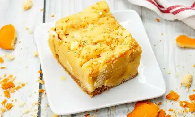 Close-up of a gooey Banana Blondies Recipe square on parchment, showing a golden vanilla-wafer crust, white chocolate pockets, and a fork ready to dig in.