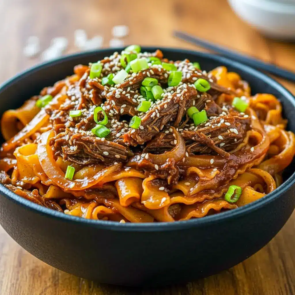 Steaming bowl of glossy shredded beef tossed with udon noodles, topped with sesame seeds and fresh cilantro, Korean Beef Noodles Recipe.