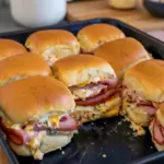 Golden, butter-brushed ham sliders on a wooden board, a perfect example of Sandwiches With Hawaiian Rolls, Sandwiches On Hawaiian Rolls, and easy Sandwich Recipes With Hawaiian Rolls, also adaptable for Sliders Cold Sandwich Recipes and served as a classic Sandwich On Hawaiian Rolls, Sandwiches Using Hawaiian Rolls.