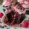 Close-up of Chocolate Lava Cupcakes split open to show a molten raspberry center, piped raspberry buttercream, fresh raspberry, and dark chocolate shavings on top.
