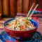 Close-up bowl of Kani Salad Recipe with shredded crab sticks, julienned cucumber and carrot, creamy spicy mayo dressing, and sesame seeds — a vibrant, chilled Japanese-style salad.