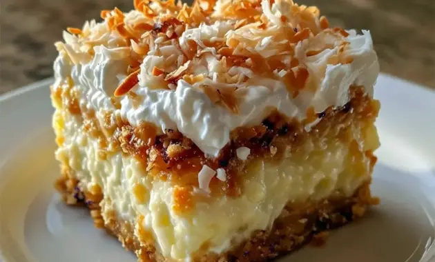 Overhead shot of Coconut Cream Dream Bars on a plate — chilled coconut squares topped with whipped cream and toasted coconut flakes, ready to serve.