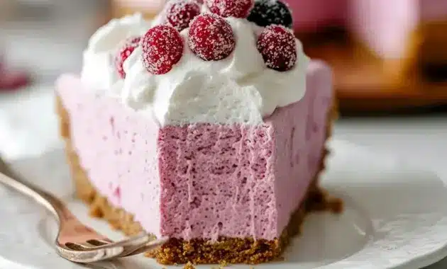 Cranberry Mousse Pie slice on a white plate, topped with whipped cream, sugared cranberries, and a rosemary sprig.
