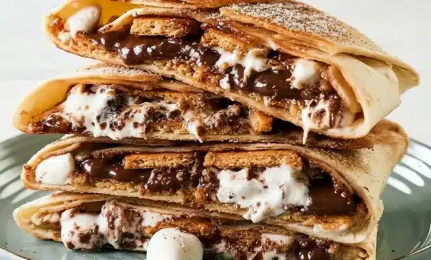 Close-up of a halved S’mores Crunchwrap showing oozing chocolate and marshmallow with a golden, cinnamon-sugar coated tortilla.
