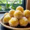 A platter of Pineapple Christmas Balls rolled in shredded coconut and arranged with festive greenery — a colorful Pineapple Recipes holiday treat ready to serve.
