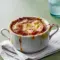 French Onion Soup Recipe — steaming bowl of onion soup topped with a toasted baguette slice and bubbling, browned cheese under the broiler.