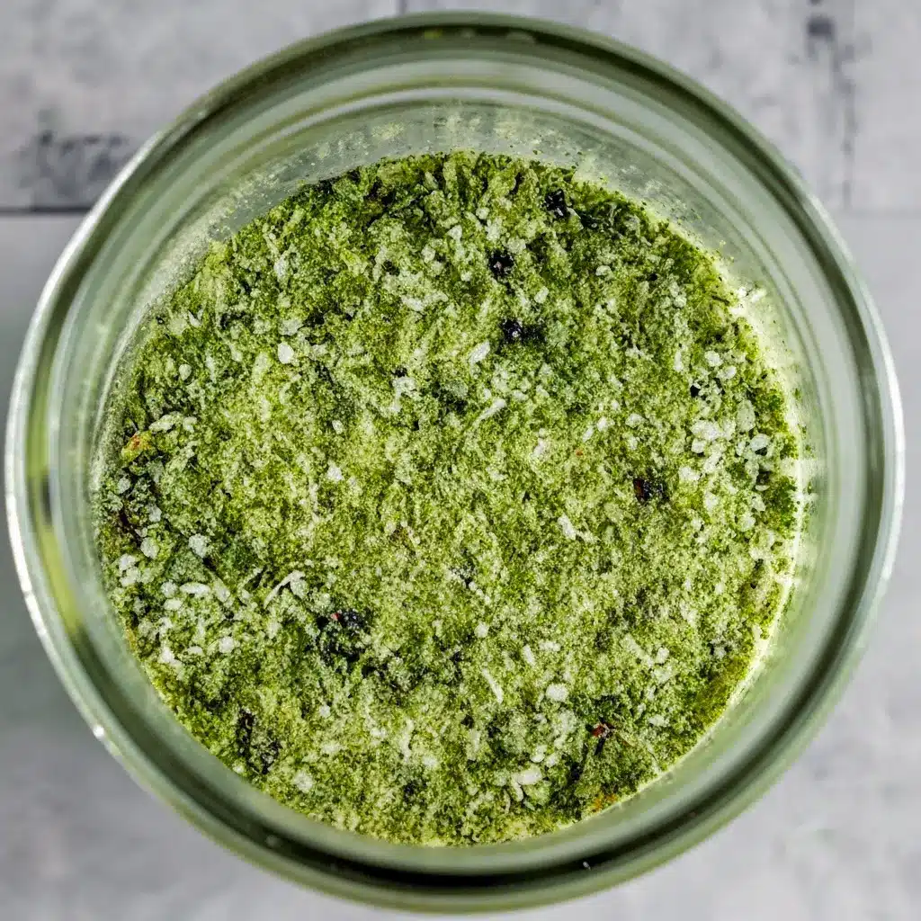 Jar of green-speckled Jalapeno Salt Recipe with fresh jalapeños and a lime wedge — a simple example of Infused Salt Recipes.