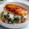 Sliced Stuffed Chicken Breast showing mushroom, spinach, and gooey cheese filling on a plate with greens — close-up, golden-baked.