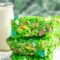 Close-up of a green Lucky Charms Rice Krispie square with marshmallow bits and a glossy finish — St Pats Day Snacks and St Patrick Day Treats styled on a festive platter.