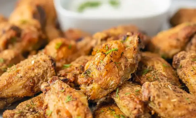 Close-up of crispy Dill Pickle Chicken Wings glazed with dill and served with a bowl of creamy Pickle Wing Sauce — a tangy Pickle Juice Wings favorite.