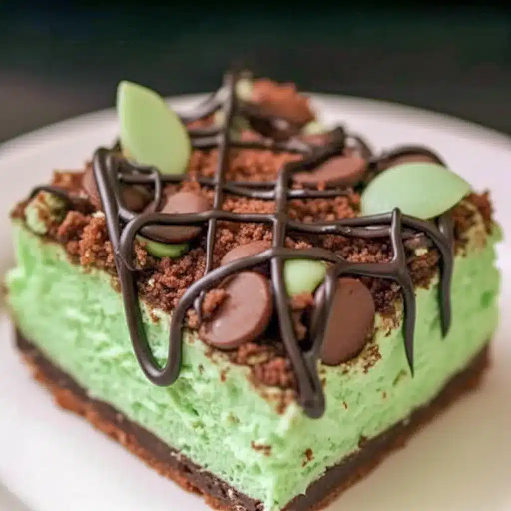 Slice of Mint Chocolate Cheesecake bar on a plate — vivid green mint cheesecake layer over a chocolate crumb crust, drizzled chocolate, and festive sprinkles for Saint Patrick's Day, a tempting example of elegant Cheesecake Bars.