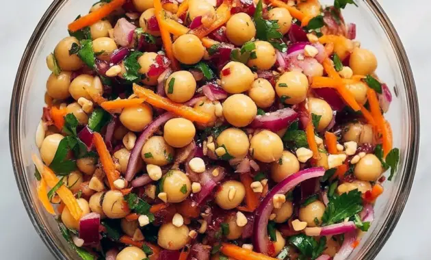 Bowl of Asian Chickpea Salad with shredded red cabbage, diced bell pepper, chickpeas, chopped peanuts, and a creamy tahini-lime dressing.