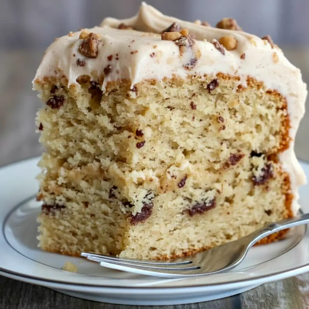 Banana Toffee Cake — slice showing banana-speckled crumb, glossy browned-butter toffee buttercream, and scattered toffee bits on top.
