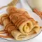 Plate of Cinnamon Roll Protein Crepes rolled and dusted with cinnamon, showing the creamy filling — a tasty example of Super Simple High Protein Meals.