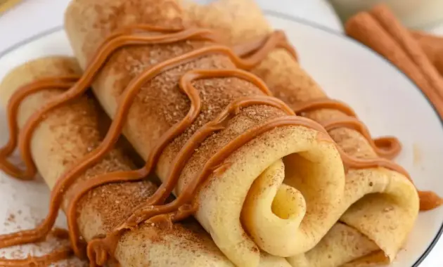 Plate of Cinnamon Roll Protein Crepes rolled and dusted with cinnamon, showing the creamy filling — a tasty example of Super Simple High Protein Meals.