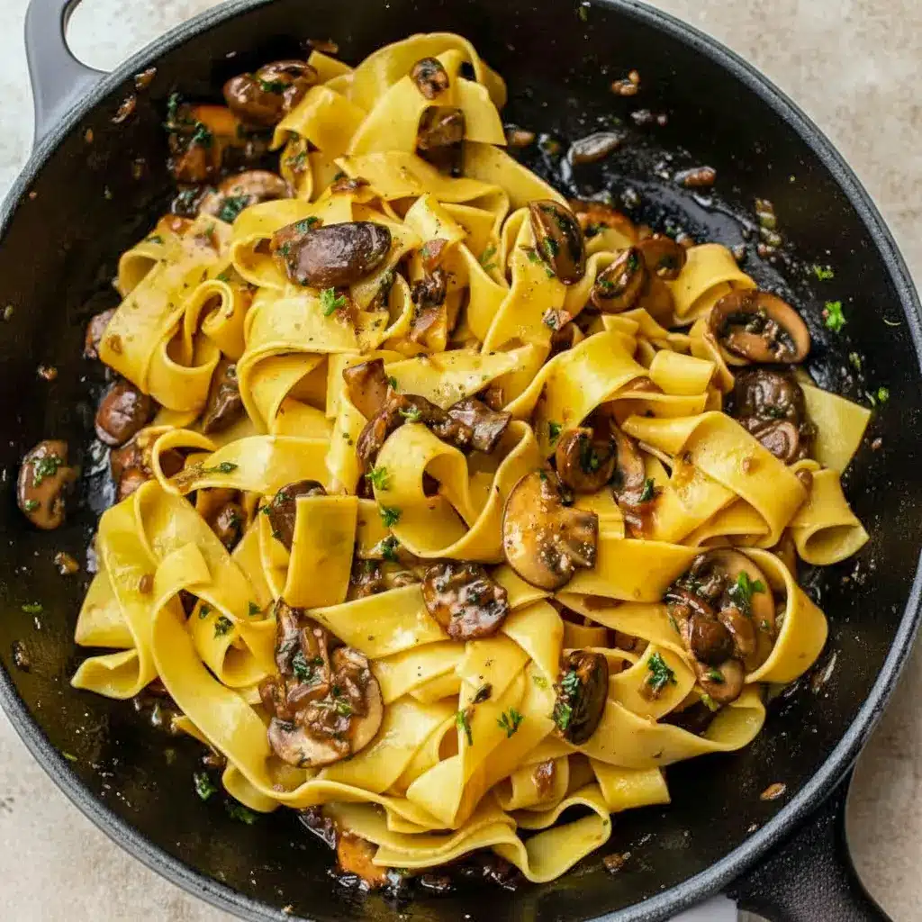 Garlic Mushroom Pasta in a shallow bowl: creamy sauce coating fettuccine, golden-browned mushrooms, grated Parmesan, and a sprinkle of parsley.