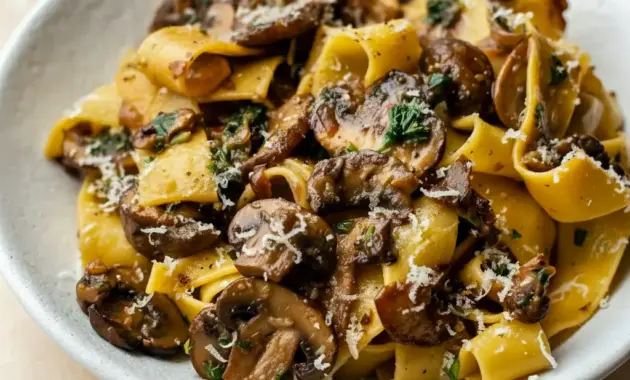Garlic Mushroom Pasta in a shallow bowl: creamy sauce coating fettuccine, golden-browned mushrooms, grated Parmesan, and a sprinkle of parsley.