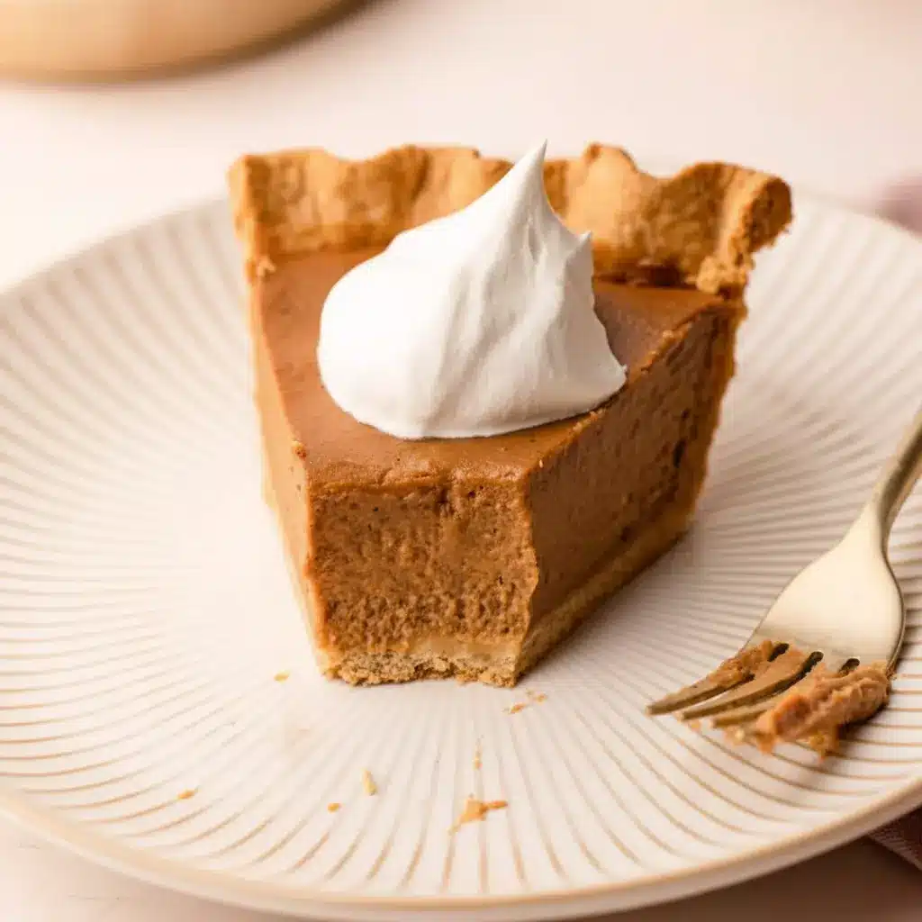 Slice of Apple Butter Pie on a plate with a dollop of maple whipped cream, showing creamy filling and a golden crust — a classic Fall Baking and Holiday Desserts favorite.