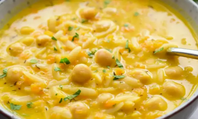 Bowl of Lemon Chickpea Orzo Soup with chickpeas, orzo, and a sprinkle of parsley in a golden, lemony broth.