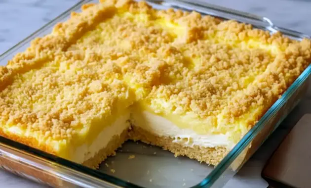 Lemon Cream Cheese Dump Cake — slice of golden crumb-topped cake showing bright lemon filling and a creamy layer, plated with a dollop of whipped cream.